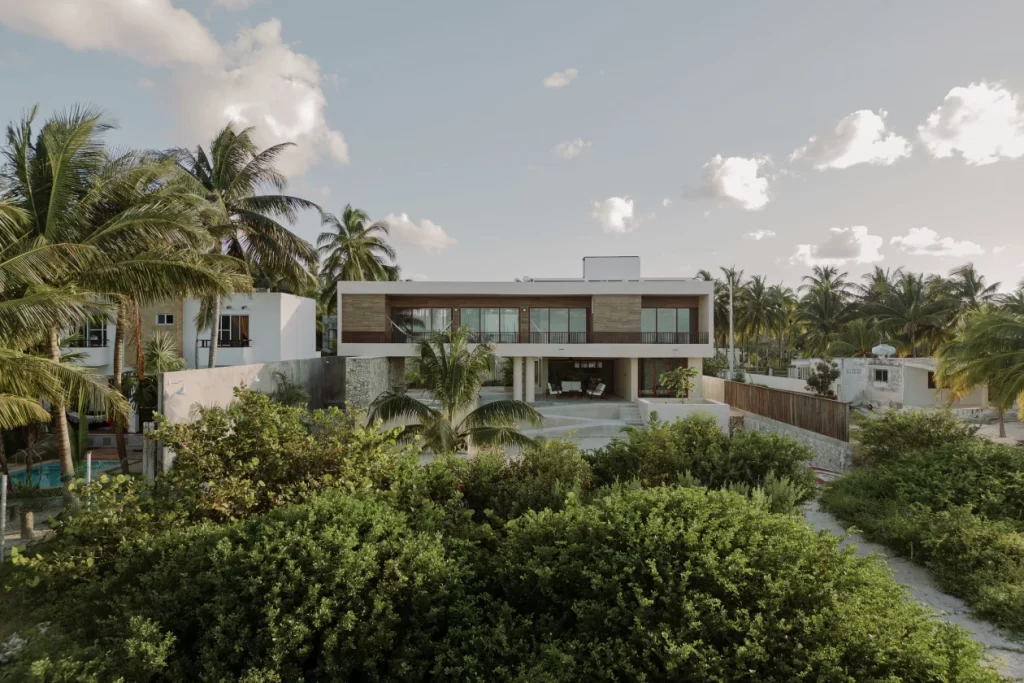 Vista exterior de Dune House, una vivienda contemporánea en la costa yucateca integrada entre dunas, vegetación nativa y palmeras.